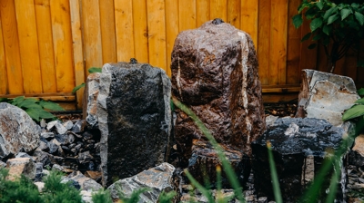 Water feature with large rocks, gravel, and greenery. Photo
